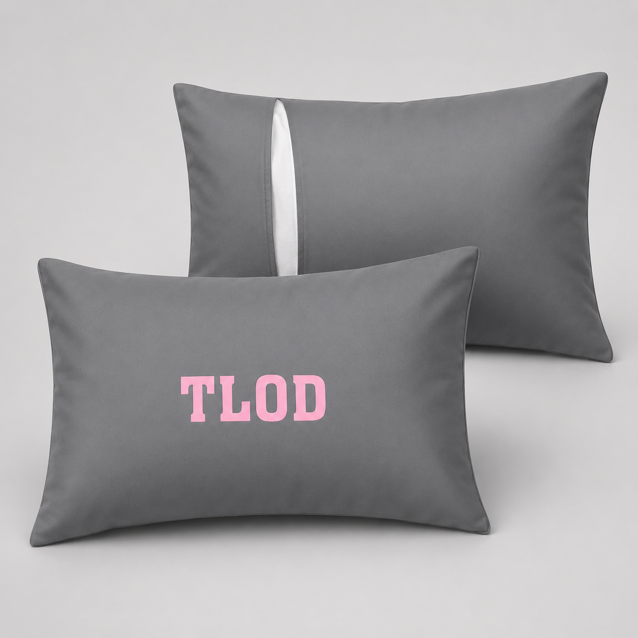 Two gray pillows with 'TLOD' printed in pink on a light gray background